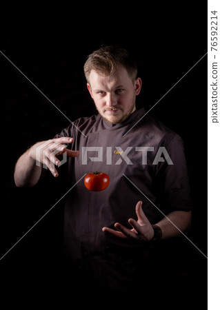 Cook magician demonstrates the trick of holding a tomato with the power of mind 76592214