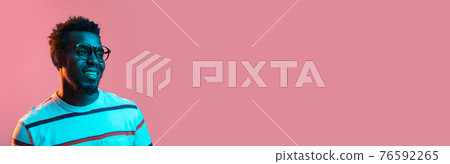 Close-up young African-American man isolated on pink background in neon Close-up young African-American man isolated on pink background in neon 76592265