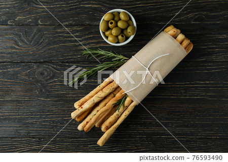 Craft paper with grissini, olives and rosemary on wooden background Craft paper with grissini, olives and rosemary on wooden background 76593490