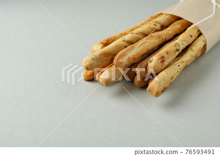 Craft paper with grissini breadsticks on light gray background Craft paper with grissini breadsticks on light gray background 76593491