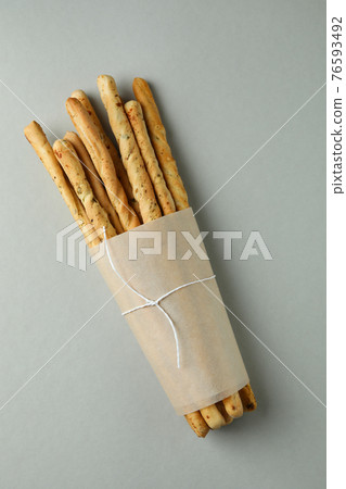 Craft paper with grissini breadsticks on light gray background 76593492