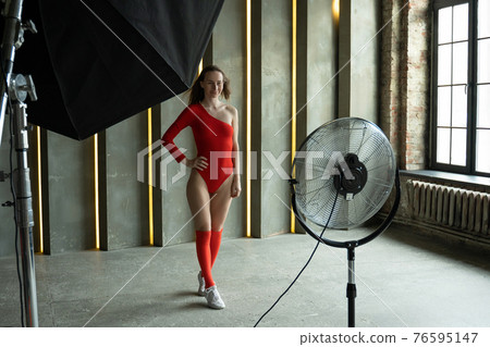 Young fashion model woman with perfect slim body posing in red bodysuit. Fashion studio shot. Young fashion model woman with perfect slim body posing in red bodysuit. Fashion studio shot. 76595147