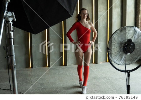 Young fashion model woman with perfect slim body posing in red bodysuit. Fashion studio shot. Young fashion model woman with perfect slim body posing in red bodysuit. Fashion studio shot. 76595149