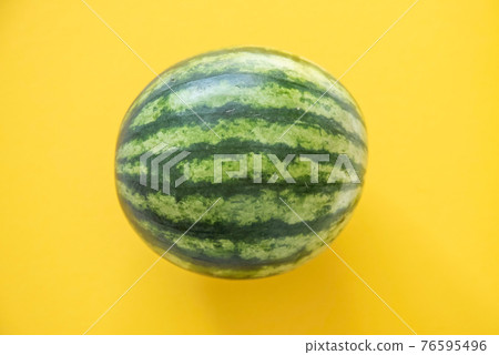 Green watermelon on yellow background top view Green watermelon on yellow background top view 76595496