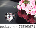 Three excellent diamonds of the first water and bouquet of pink roses with reflection on black mirror background close up view. Jewelry diamonds sale, invitation, action, discount banner, poster 76595671