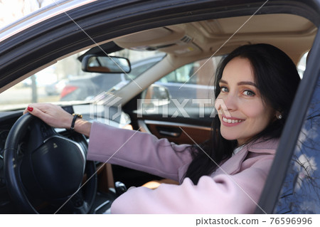 Portrait of smiling woman driving car closeup 76596996
