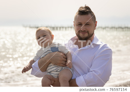 Happy father on vacation - man hugging his little baby son Happy father on vacation - man hugging his little baby son 76597154