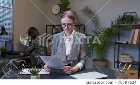 Displeased upset young businesswoman accountant reading documents, analyzing financial papers data Displeased upset young businesswoman accountant reading documents, analyzing financial papers data 76597624