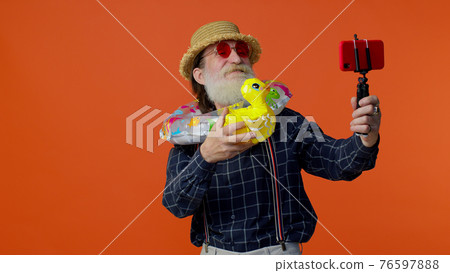 Mature grandfather traveler blogger in sunglasses, taking selfie on mobile phone, video call online Mature grandfather traveler blogger in sunglasses, taking selfie on mobile phone, video call online 76597888