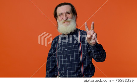 Senior bearded man showing victory sign, hoping for success and win, doing peace gesture and smiling 76598359