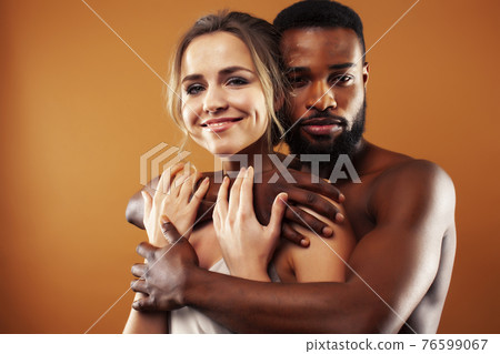 Young pretty couple diverse races together posing sensitive on brown background, lifestyle people concept Young pretty couple diverse races together posing sensitive on brown background, lifestyle people concept 76599067