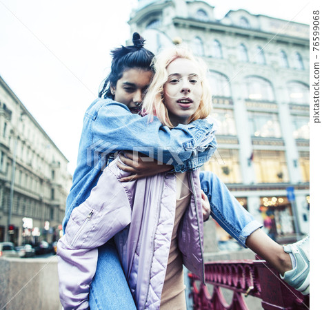Two teenage girls infront of university building smiling, having fun, lifestyle real people concept Two teenage girls infront of university building smiling, having fun, lifestyle real people concept 76599068