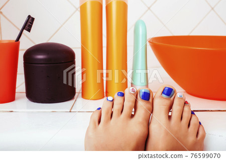 woman legs in bathroom with lot of stylish stuff for care, pedicure creative design, hygiene spa mani pedi concept woman legs in bathroom with lot of stylish stuff for care, pedicure creative design, hygiene spa mani pedi concept 76599070