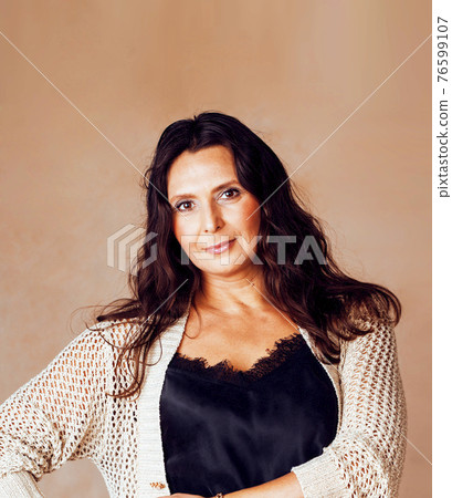pretty brunette confident mature woman posing cheerful on warm brown background, lifestyle people concept pretty brunette confident mature woman posing cheerful on warm brown background, lifestyle people concept 76599107