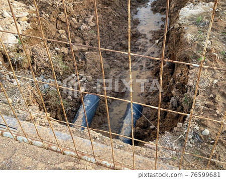 An excavated pit is a ditch for laying cables and wires with pipes under the ground during the construction and repair of houses in the city of the megalopolis 76599681