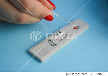 test for coronavirus on a blue background. girl with a bright red manicure makes a blood test. a small test tube is dripped with a saline solution onto the test strip test for coronavirus on a blue background. girl with a bright red manicure makes a blood test. a small test tube is dripped with a saline solution onto the test strip 76599693