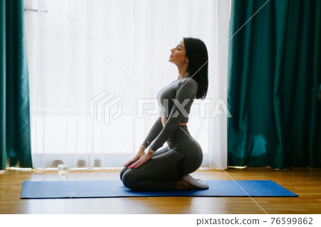 Young attractive woman practicing yoga at home. stretching practice 76599862