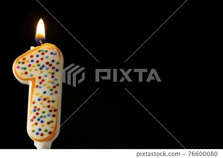 Number 1 birthday celebration candle against a black background. Copy space for text 76600080