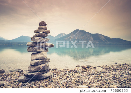 Hobby of rock stacking at Alps lake. Balanced stones on a pebble beac 76600363