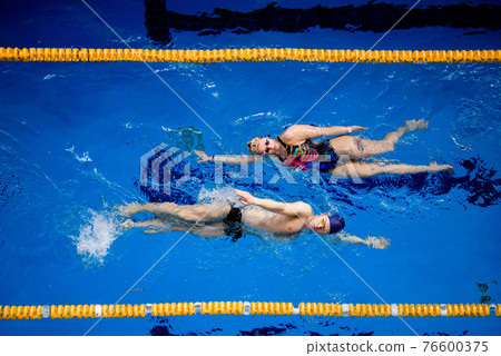 Training of professional swimmers. Athletes swim on their backs in the pool. Training of professional swimmers. Athletes swim on their backs in the pool. 76600375
