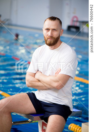 A young swimming coach near the sports pool. 76600442