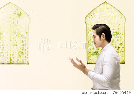 Asian Muslim man standing while raised hands and praying Asian Muslim man standing while raised hands and praying 76605449