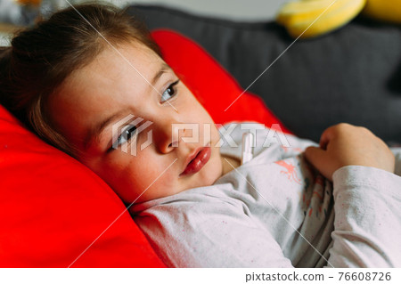 Toddler girl with mercury thermometer lying at home. Kid having high body temperature. Sick, fewer 76608726