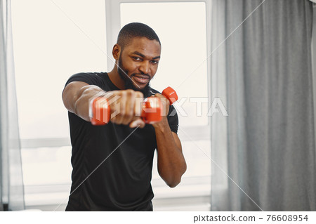 Handsome Afro American sportsman working out at home Handsome Afro American sportsman working out at home 76608954