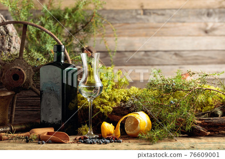 Gin in a small glass and an antique bottle of dark glass. Gin in a small glass and an antique bottle of dark glass. 76609001