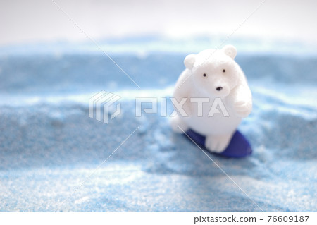 A polar bear figure surfing on the blue sand that looks like a wave 76609187