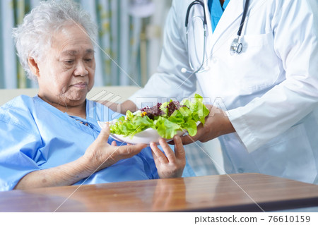 Asian senior or elderly old lady woman patient eating breakfast vegetable healthy food with hope and happy while sitting and hungry on bed in hospital. Asian senior or elderly old lady woman patient eating breakfast vegetable healthy food with hope and happy while sitting and hungry on bed in hospital. 76610159