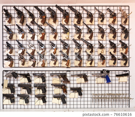 Gun shop interior with handguns displayed on rack Gun shop interior with handguns displayed on rack 76610616