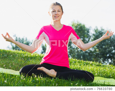 Adult female in pink T-shirt is sitting and doing meditation Adult female in pink T-shirt is sitting and doing meditation 76610780