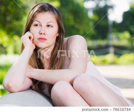 Young female is sitting sad and lonely Young female is sitting sad and lonely 76610784