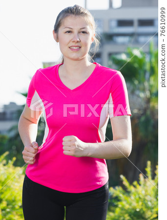Female 20-30 years old in pink T-shirt is jogging 76610999