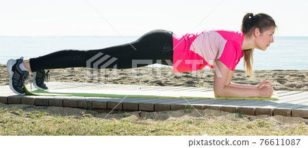 Girl practicing yoga poses on beach 76611087