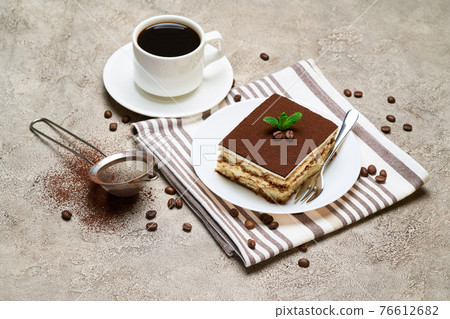 Portion of Traditional Italian Tiramisu dessert and cup of coffee on grey concrete background Portion of Traditional Italian Tiramisu dessert and cup of coffee on grey concrete background 76612682
