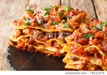 Vincisgrassi are flat pasta, a meat sauce called ragu,  the variety of meats is coarsely chopped and mixed with cloves, celery, onion, carrot, chicken giblets, tomatoes closeup. horizontal 76612978