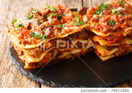 Lasagna Vincisgrassi Recipe with chicken giblets, beef, pork and vegetables close-up on a slate board. horizontal 76612980