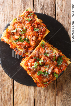 Italian Vincisgrassi or vincesgrassi, is a typical Marche pasta dish similar to lasagne al forno closeup in the slate board. Vertical top view Italian Vincisgrassi or vincesgrassi, is a typical Marche pasta dish similar to lasagne al forno closeup in the slate board. Vertical top view 76612984