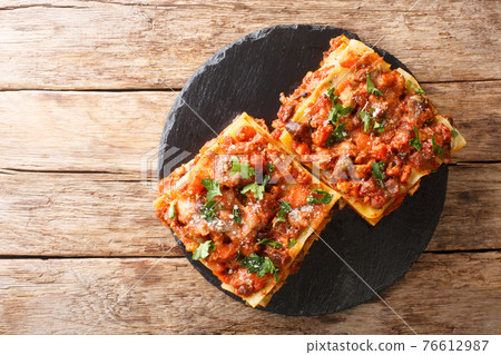 Italian pasta Vincisgrassi with chicken giblets, beef, pork, cheese and vegetables close-up on a slate board. horizontal top view 76612987