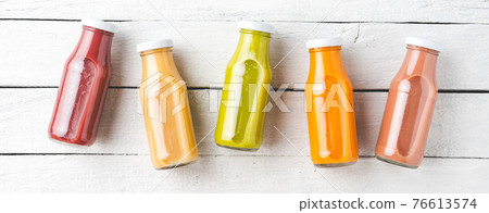 Fresh fruit and vegetable smoothies in bottles on white wooden table. Banner 76613574