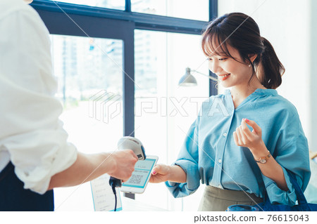 Young woman making a smartphone payment 76615043