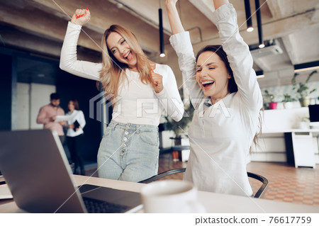 Two young happy businesswomen celebrating project success in office Two young happy businesswomen celebrating project success in office 76617759
