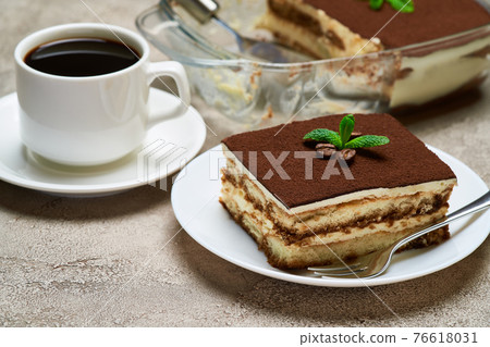 Traditional Italian Tiramisu dessert in glass baking dish and portion on grey concrete background 76618031