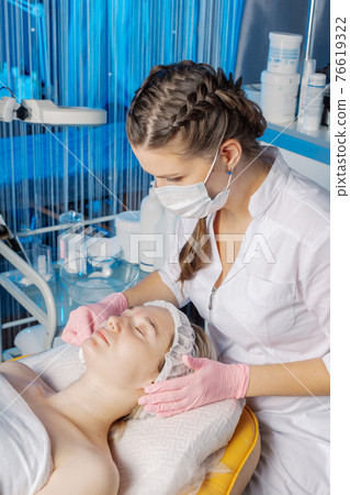 Professional beautician wipes a woman's face after 76619322