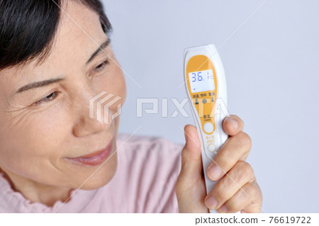 Senior woman relieved to have a non-contact thermometer temperature of 36.1 degrees 76619722