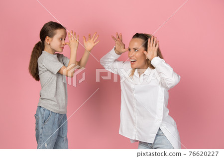 Young woman and girl, mother and daughter isolated over pink background. 76620227