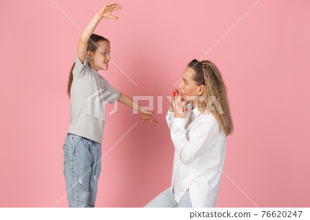 Young woman and girl, mother and daughter isolated over pink background. Young woman and girl, mother and daughter isolated over pink background. 76620247