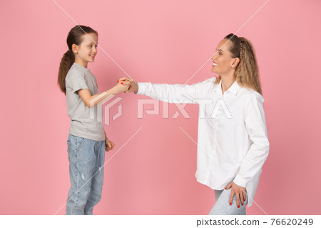 Young woman and girl, mother and daughter isolated over pink background. Young woman and girl, mother and daughter isolated over pink background. 76620249